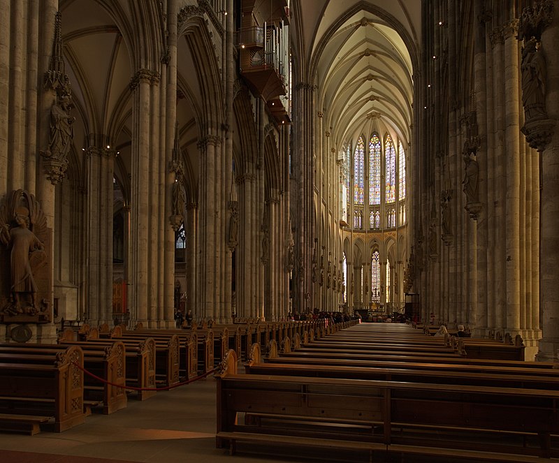 Interior de la catedral de Colonia (Alemania). Se observan los arcos apuntados de las naves, las bóvedas de crucería y los vitrales de la cabecera de la iglesia.