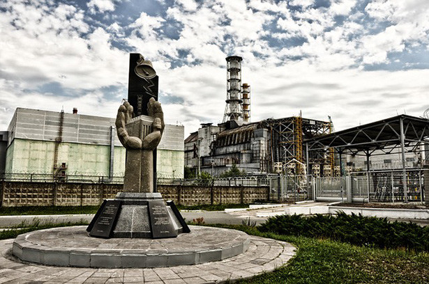 Monumento a las víctimas del accidente de Chernóbil. De fondo, el reactor número 4, causante del accidente.