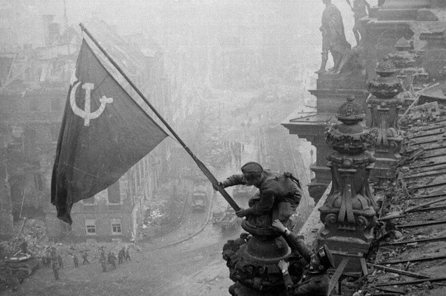 Fotografía de Yevgeni Jaldéi que muestra a soldados rusos haciendo flamear una bandera soviética en los techos del edificio del Reichstag, el 30 de abril de 1945.